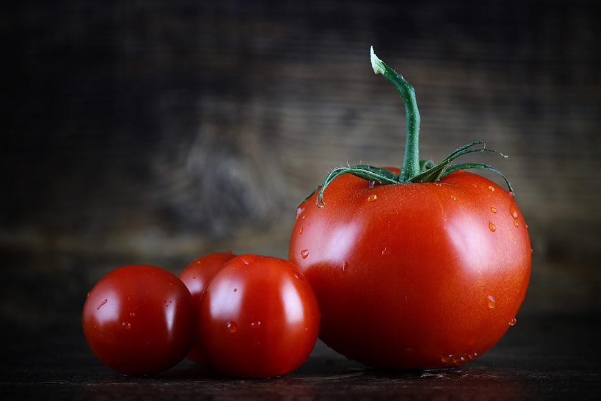 Fresh Red Tomatoes with Water Drops on Dark Wood