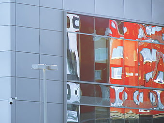 Modern building facade with distorted red glass reflections