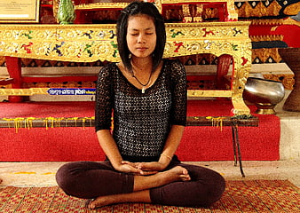 Young woman meditating in a Thai temple interior