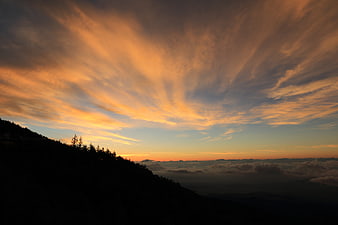 Dramatic sunset sky with golden clouds over mountain silhouette