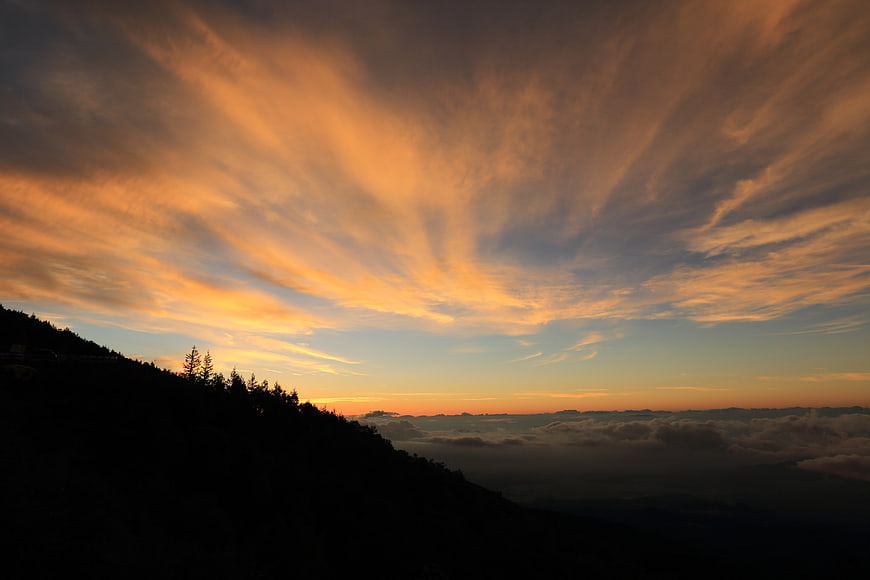 Dramatic sunset sky with golden clouds over mountain silhouette