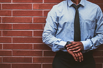 Businessman checking watch against red brick wall