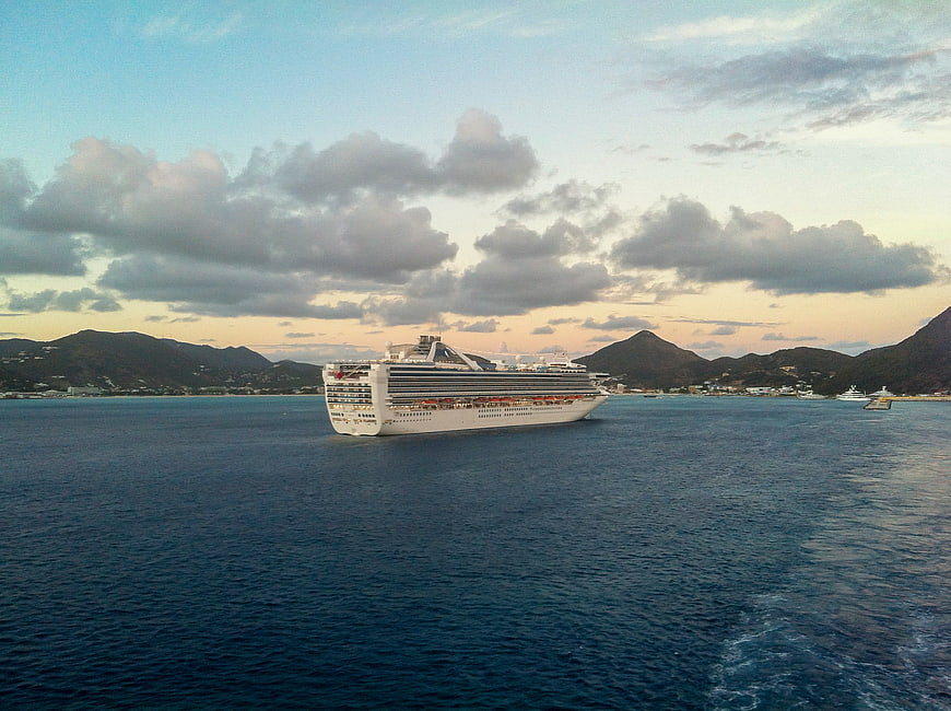 Large cruise ship sailing in tropical bay at dusk