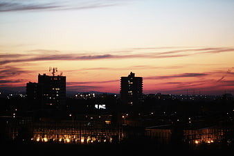 Silhouetted City Skyline at Sunset with Warm Orange Sky