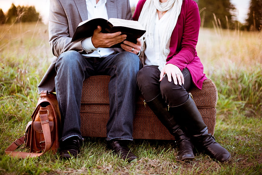 Couple Reading Bible on Outdoor Sofa in Field