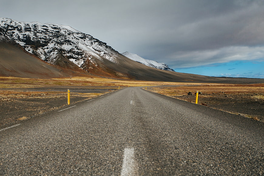 Empty asphalt road leading to snow-capped mountains in Iceland