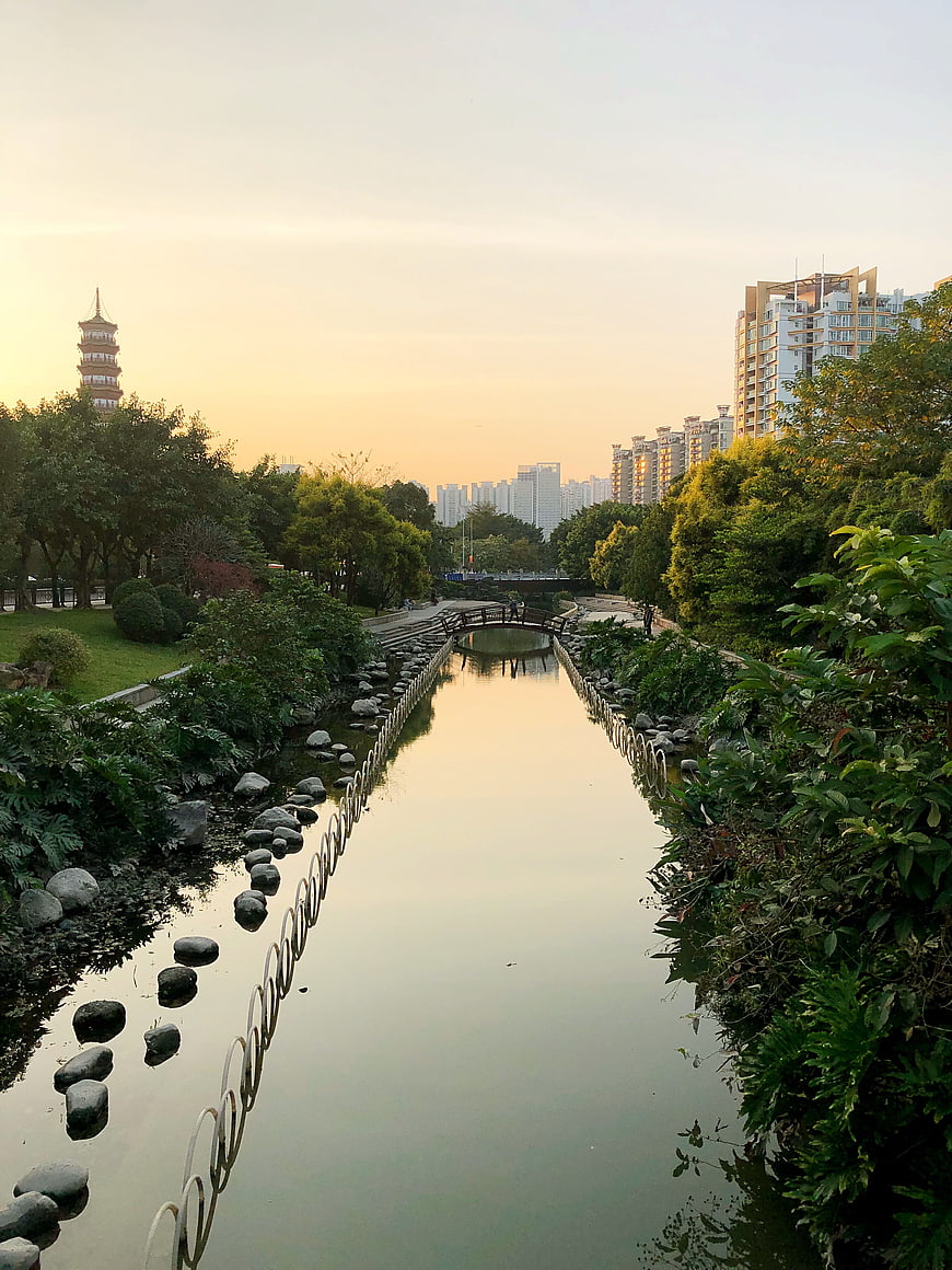 Serene urban park river with pagoda and city skyline at sunset