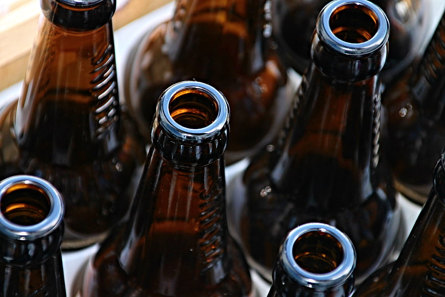 Close-up of open brown beer bottles in a crate