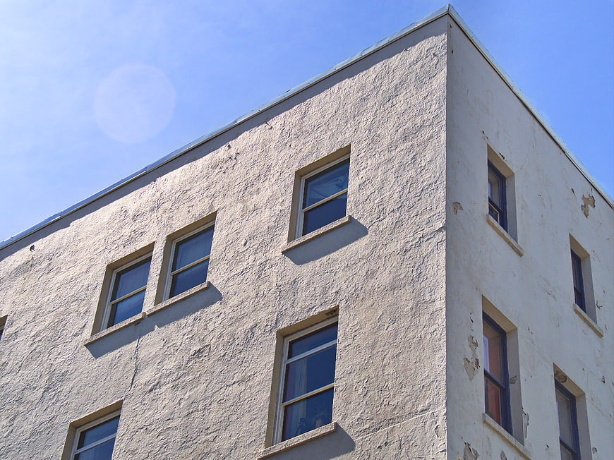 Low angle view of textured white building facade with windows