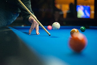 Close-up of hand aiming pool cue on blue table