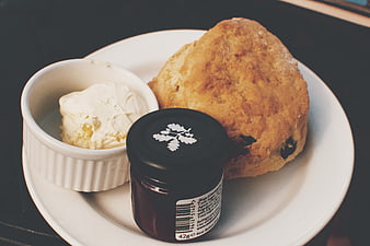 Scone with clotted cream and jam on a white plate
