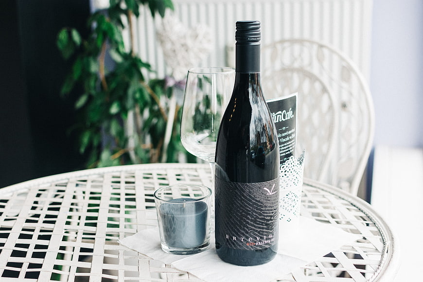 Bottle of red wine and candle on white patio table