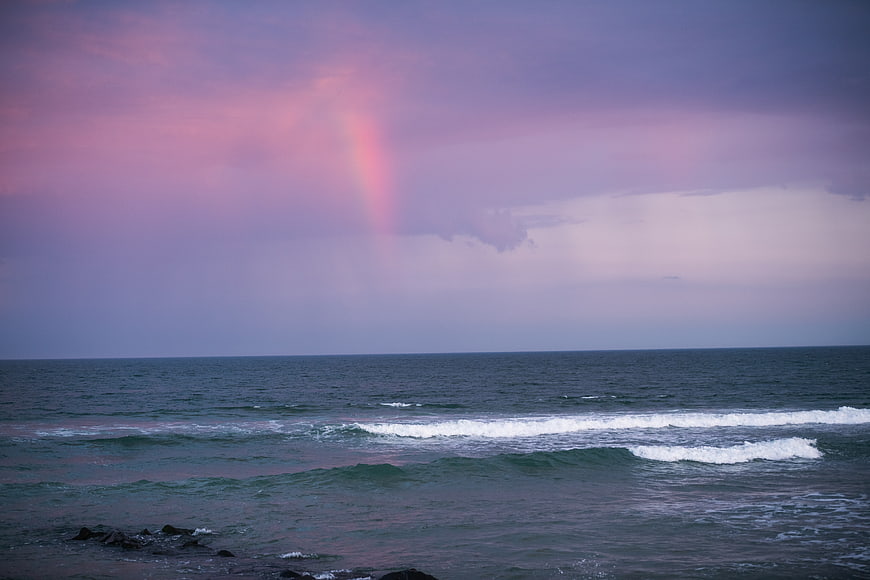 Pink Rainbow Over Ocean Waves at Dusk