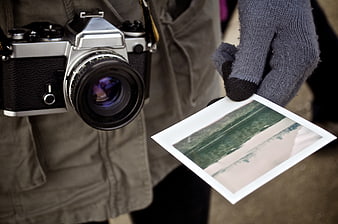 Photographer holding vintage camera and printed photo
