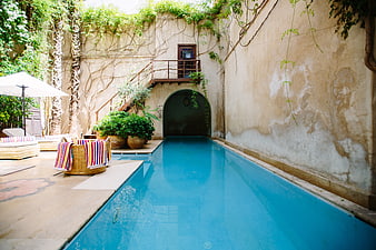 Secluded courtyard swimming pool with rustic walls and lounge chairs