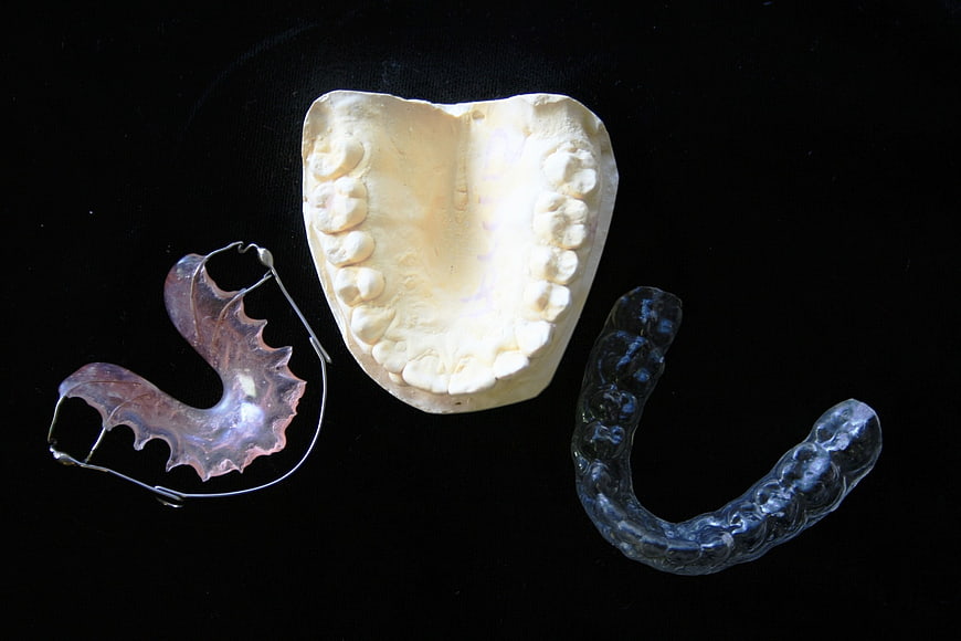 Dental impression mold, retainer, and mouthguard on black background
