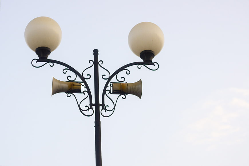 Ornate street lamp with speakers against a clear sky