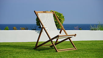 Wooden deck chair on green lawn with sea view