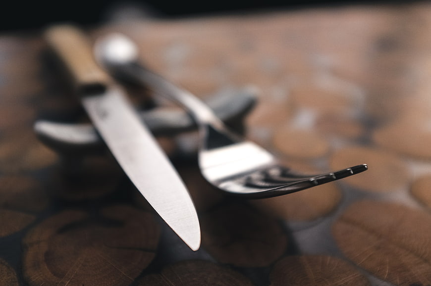 Close-up of silver fork and steak knife on wooden table