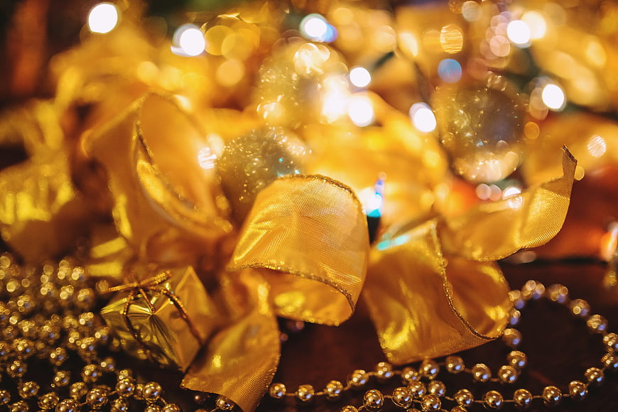 Close-up of Gold Christmas Bow and Beads with Bokeh Lights