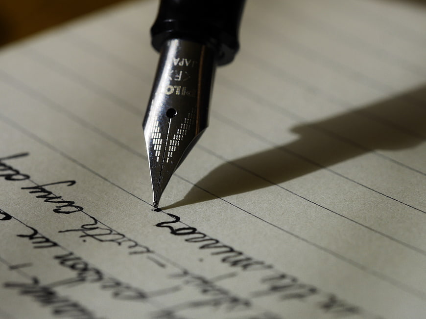 Close-up of fountain pen nib writing on lined paper