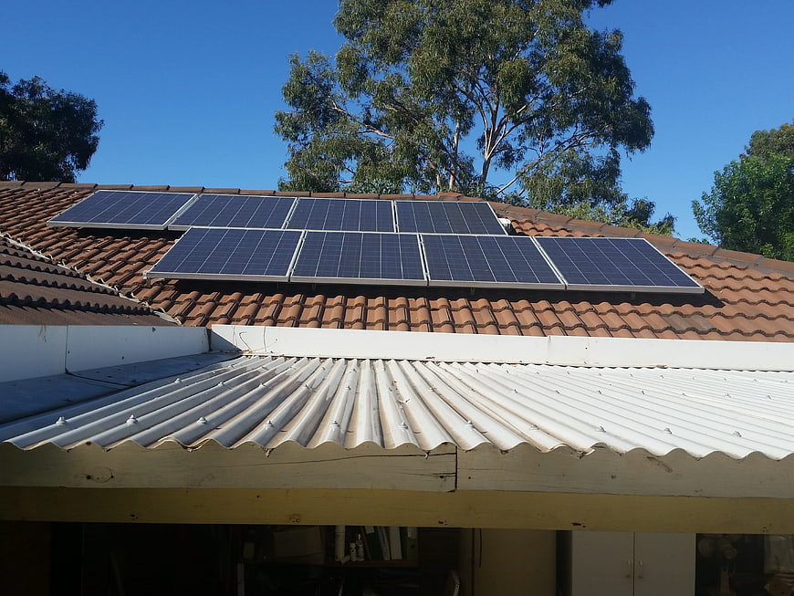 Solar panels on terracotta tiled roof with corrugated metal awning