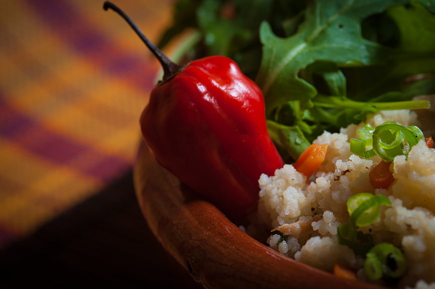 Close-up of red chili pepper on couscous salad in wooden bowl