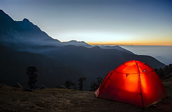 Glowing red tent in mountain landscape at sunrise