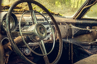 Rusty vintage car steering wheel interior with cobwebs