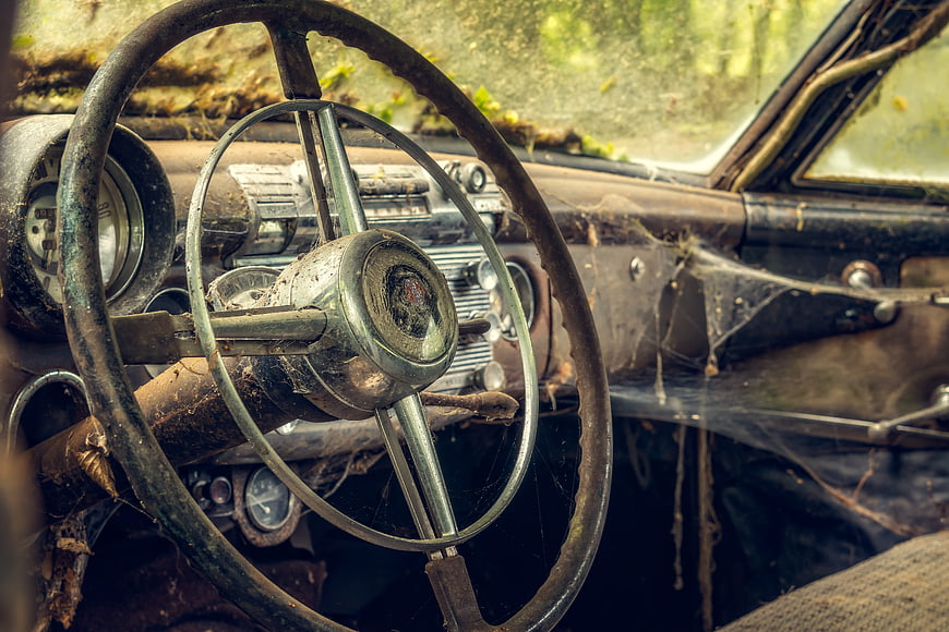 Rusty vintage car steering wheel interior with cobwebs