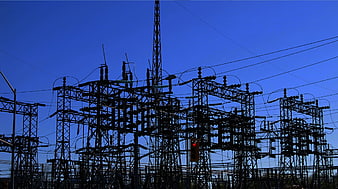 Silhouette of electrical substation against blue sky