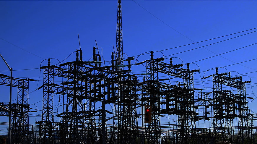 Silhouette of electrical substation against blue sky