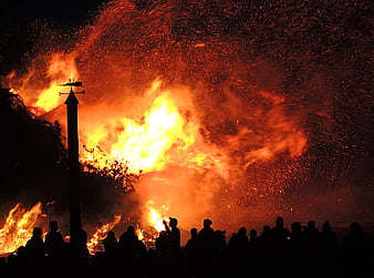 Massive bonfire with sparks and crowd silhouettes at night
