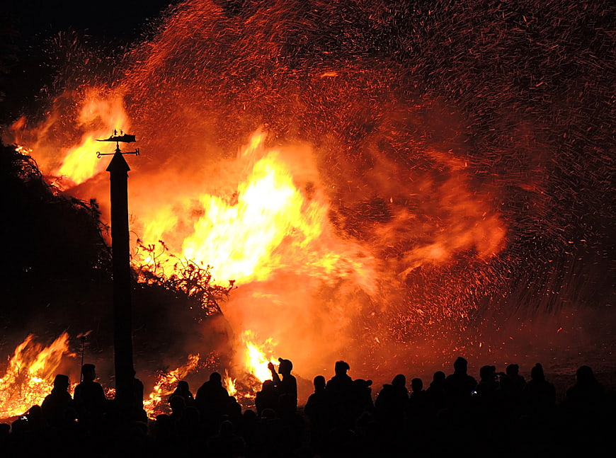 Massive bonfire with sparks and crowd silhouettes at night