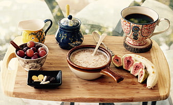 Healthy breakfast with oatmeal, fresh fruits, and coffee on a wooden tray