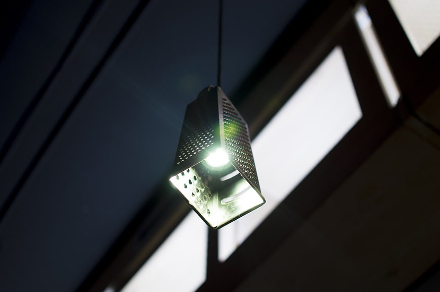 Modern perforated metal pendant light fixture hanging from ceiling