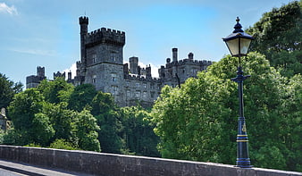 Lismore Castle in Ireland with vintage street lamp and lush green trees