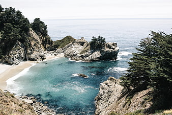 Scenic coastal cove with turquoise water, rocky cliffs, and waterfall