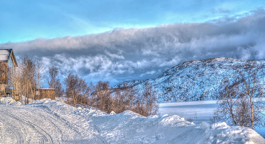 Snowy winter landscape with wooden cabin and frozen lake