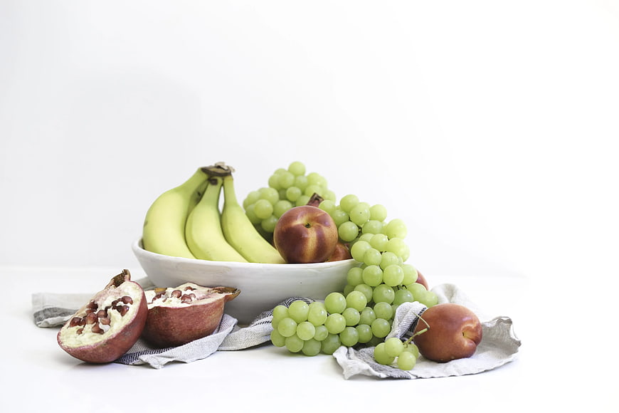 Fresh fruit arrangement with bananas, grapes, and pomegranate