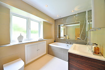 Modern beige bathroom with bathtub, sink, and large window