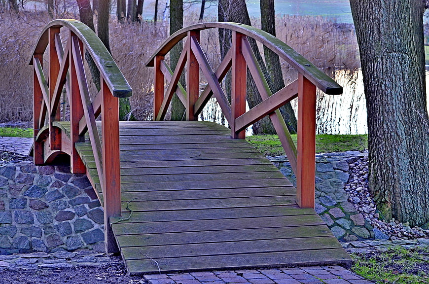 Wooden arched bridge in a park over a stream