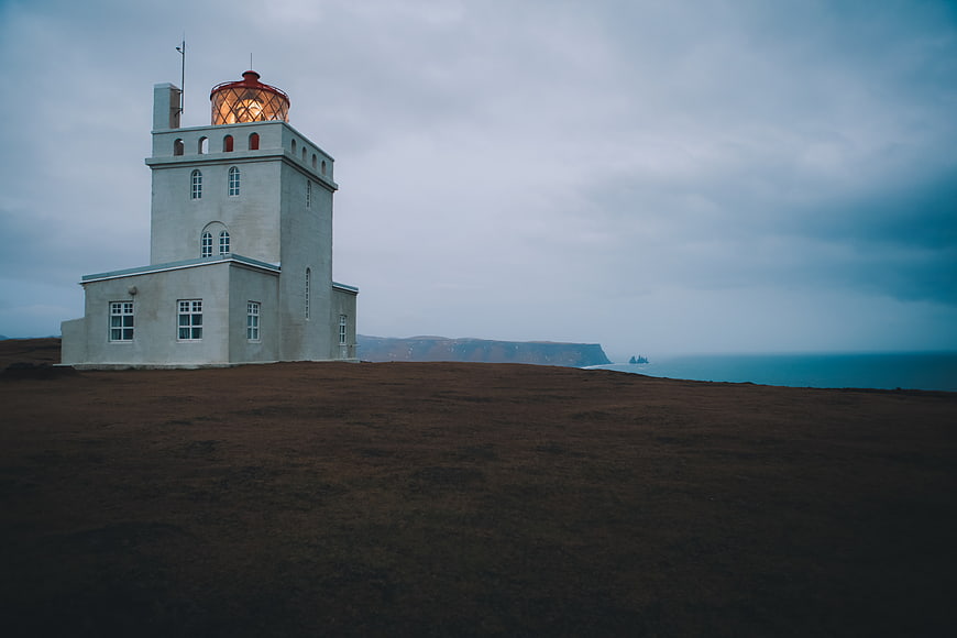 White Lighthouse on Cliff Overlooking Ocean at Dusk