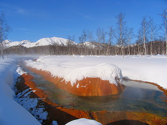 Steaming hot spring stream in snowy Kamchatka winter landscape