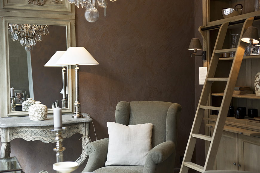 Elegant interior with gray armchair, wooden ladder, and vintage console table