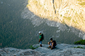 Two Hikers Resting on Granite Cliff Overlooking Yosemite Valley