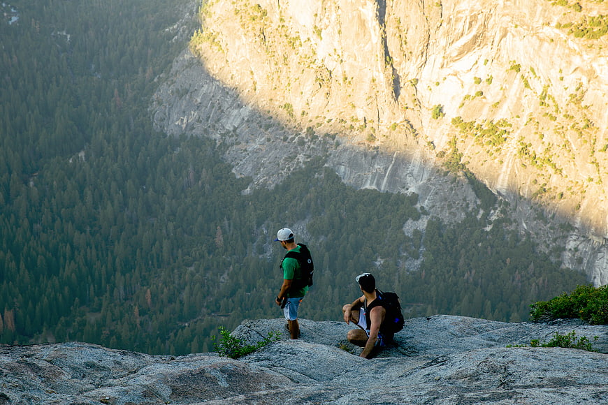 Two Hikers Resting on Granite Cliff Overlooking Yosemite Valley