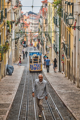 Senior man walking on tram tracks in historic Lisbon street