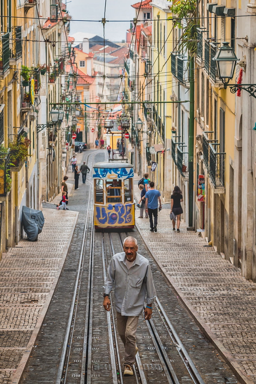 Senior man walking on tram tracks in historic Lisbon street