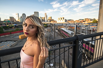 Young Blonde Woman on Urban Bridge with City Skyline